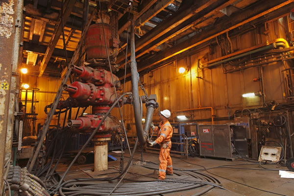 Worker in orange safety gear and white helmet operates machinery in an industrial facility