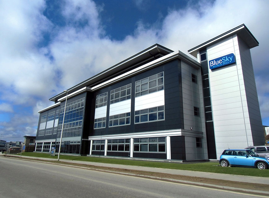 Modern office building with large windows, labeled BlueSky, situated next to a road with a blue car parked in front under a partly cloudy sky.